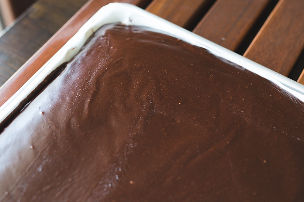 Close-up of smooth and shiny old fashioned chocolate fudge icing that sets like soft fudge on top of cake.