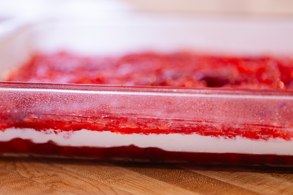 Layered strawberry jello salad with top fruit layer added before final chill.