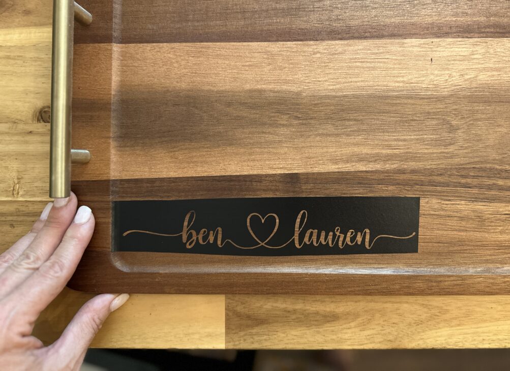 Personalized wooden charcuterie board with custom names created using a Cricut stencil, Applying a removable vinyl stencil to a wooden charcuterie board for a personalized gfit, How to make a personalized charcuterie board without engraving!