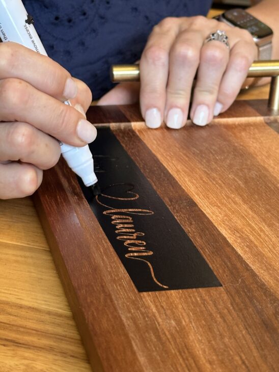 Personalized wooden charcuterie board with custom names created using a Cricut stencil, Applying a removable vinyl stencil to a wooden charcuterie board for a personalized gfit, How to make a personalized charcuterie board without engraving!